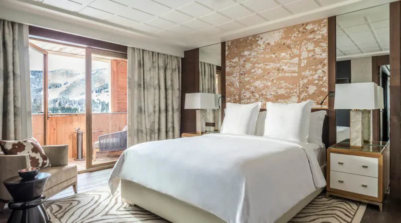 Luxurious Megève hotel suite with king bed, zebra rug, balcony view of snowy mountains.