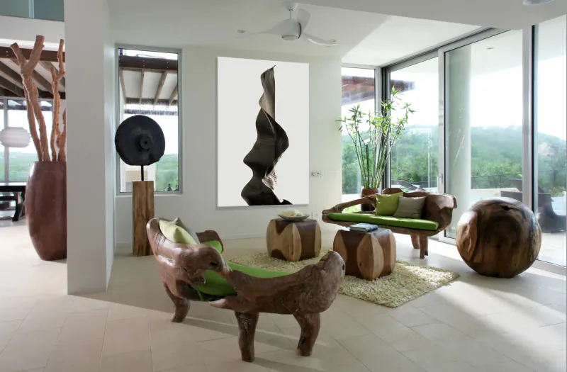 Modern tropical living room in Àni Private Resorts with carved wooden furniture, abstract wall sculpture, and lush green views.