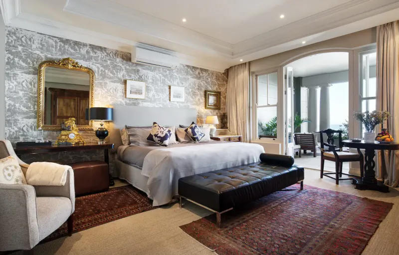Luxurious bedroom at 21 Nettleton in Clifton, Cape Town, with king bed, ornate mirrors, balcony view over Atlantic.