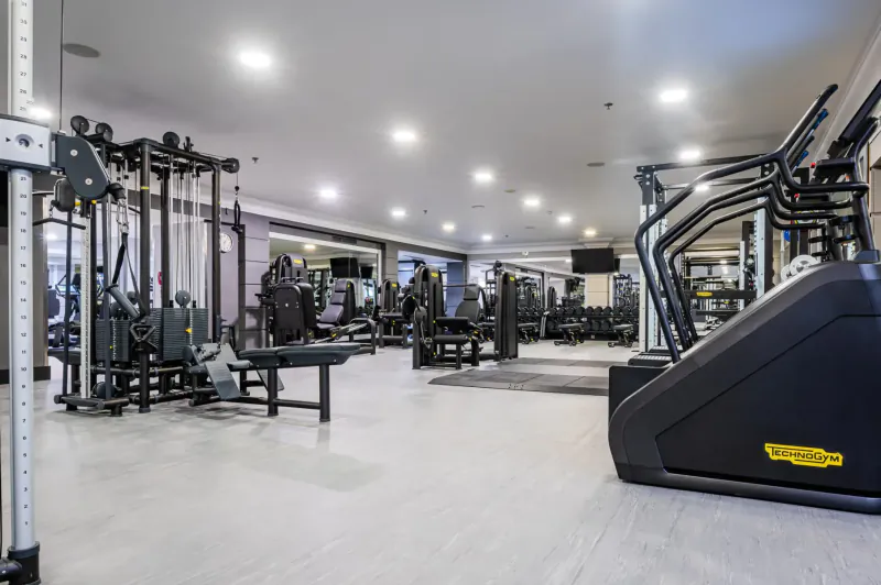 Spacious modern gym at Hilton Malta with weight machines, treadmills, and bright lighting.
