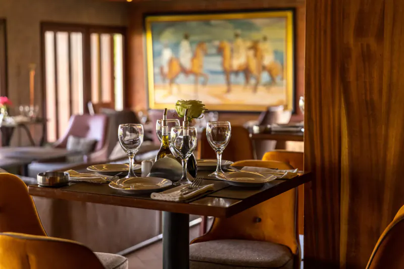 Elegant Polo Club restaurant table set with wine glasses, flowers, and polo horse painting in warm wooden interior