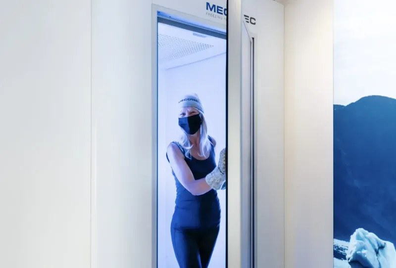 Woman in black workout gear and mask stands smiling in METC scanner at Aqua-Tox Wellness Clinic