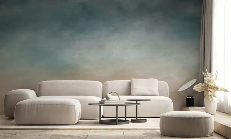 Modern living room with modular beige sofa, nested coffee tables, pouf, dried pampas grass, and teal ombre mural wallpaper.