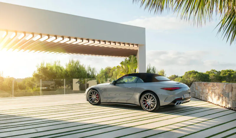 Silver Mercedes-AMG SL convertible parked on modern terrace with palms at sunset