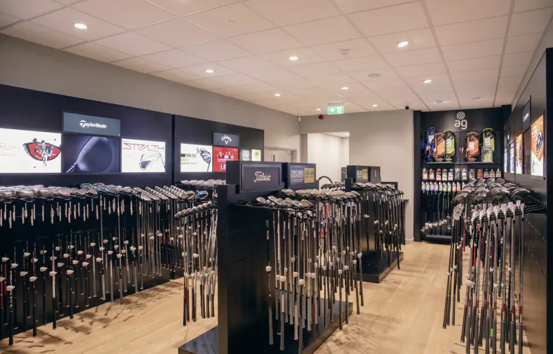American Golf store interior with TaylorMade displays and rows of golf clubs on racks