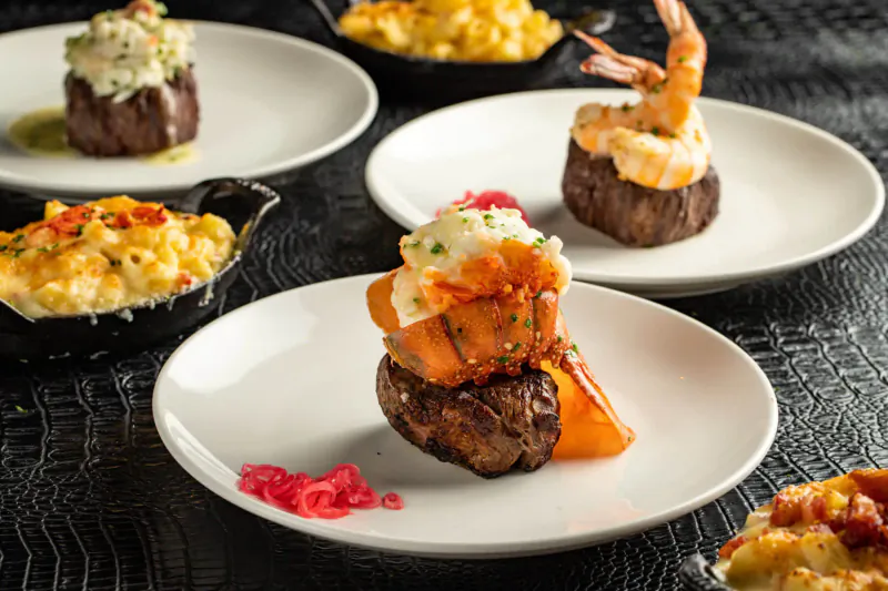 Assortment of upscale dishes at STK: seared filet mignon stacks with lobster and shrimp, creamy mac and cheese.