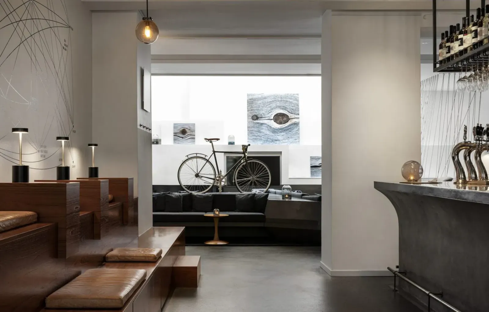 Modern Hotel SP34 lobby in Copenhagen with wooden benches, bicycle display, bar taps, and contemporary art.