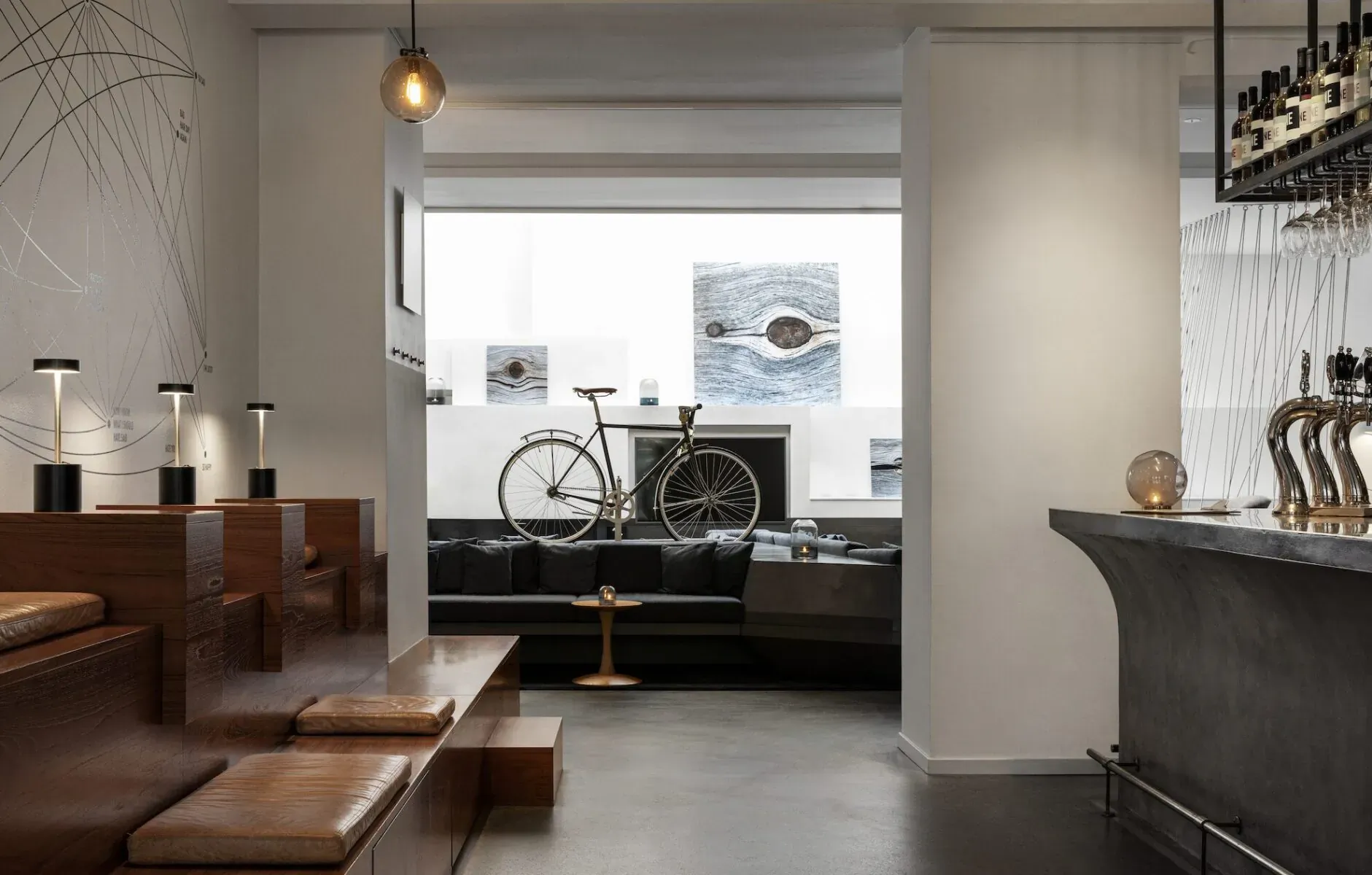 Modern Hotel SP34 lobby in Copenhagen with wooden benches, bicycle display, bar taps, and contemporary art.