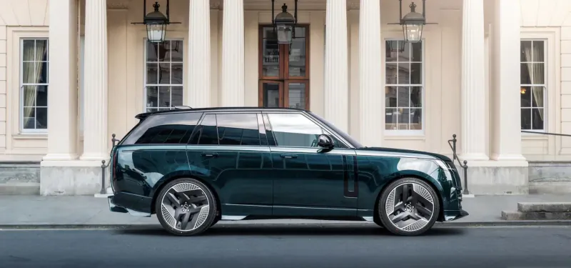 Emerald green Range Rover parked in front of elegant columned building entrance.