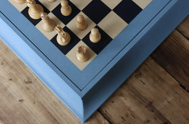 Close-up of wooden chess pieces on a blue-framed chessboard on wooden table