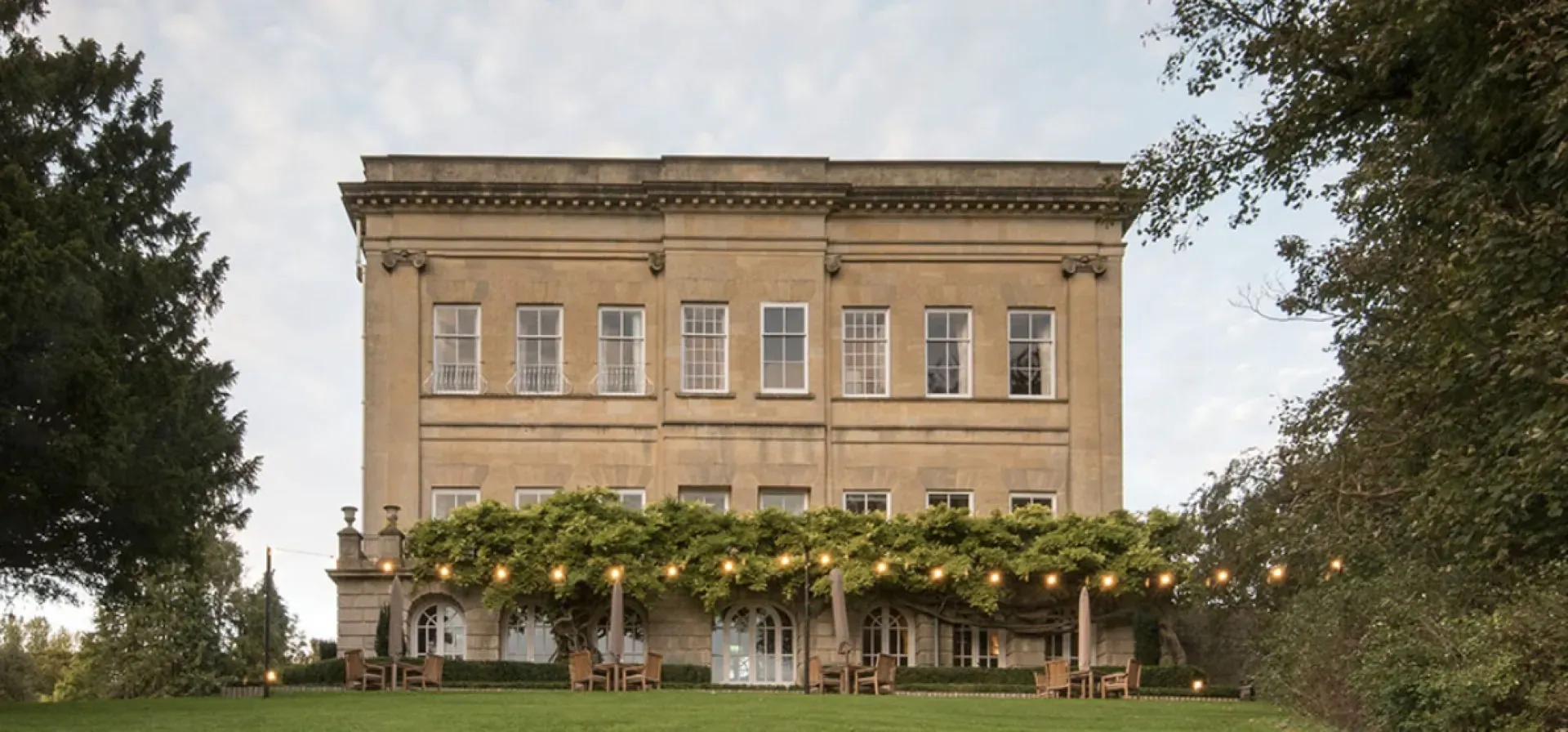 Bailbrook House Hotel, Bath's Grade II listed country house, with vine-covered terrace, fairy lights, and trees on lawn
