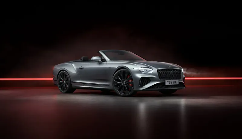 Silver Bentley Continental GT Black Edition convertible with black wheels and red light trails on dark background