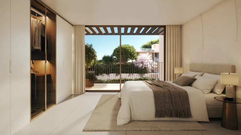 Spacious modern bedroom in Vale Do Lobo Resort with king bed, open wardrobe, and terrace view of lush gardens and sea.