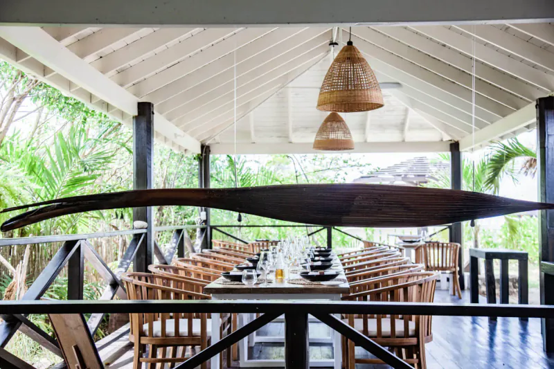 Long wooden paddle above elegantly set dining table in tropical open-air pavilion at Casa Roots.