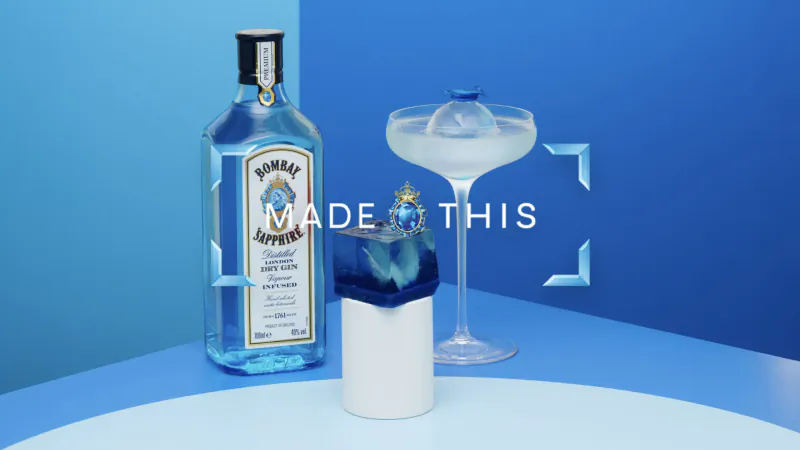 Bombay Sapphire gin bottle beside white glass with ice dome cocktail on blue surface, 'MADE THIS' text overlay.