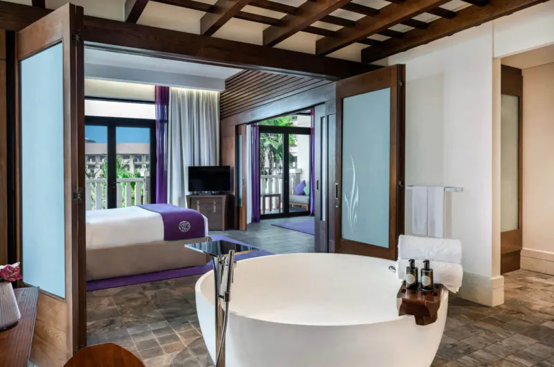 Luxurious Sofitel Dubai The Palm suite with king bed, freestanding bathtub, and balcony view of palms.