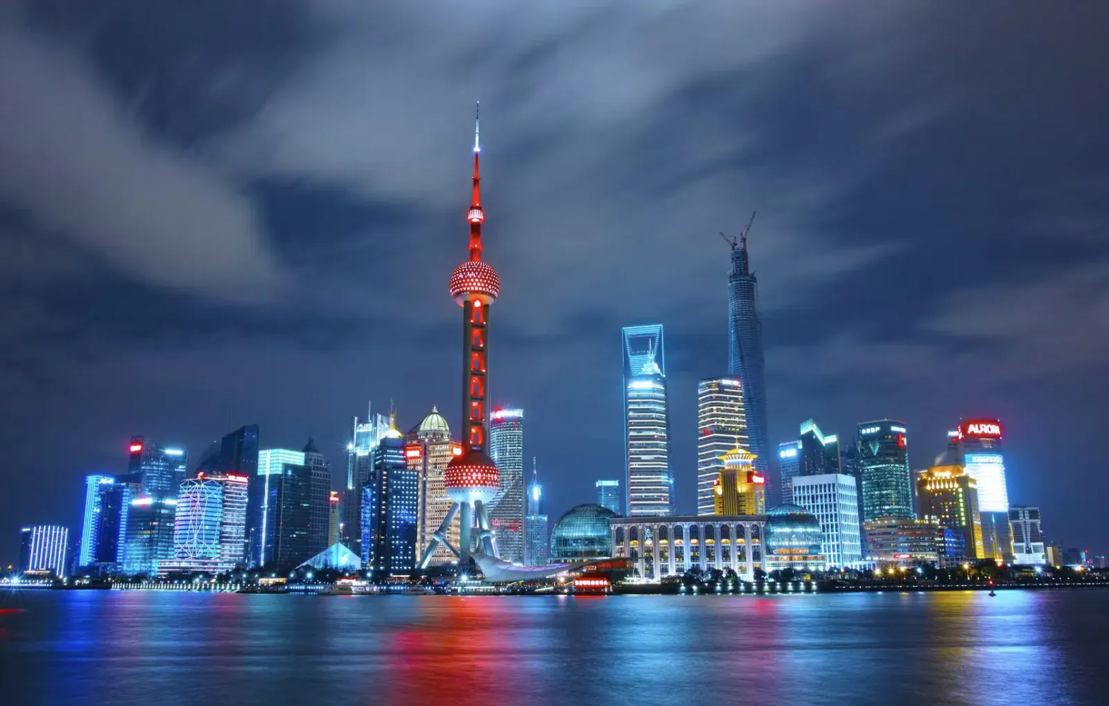 Shanghai skyline at night with Oriental Pearl Tower illuminated over reflective Huangpu River