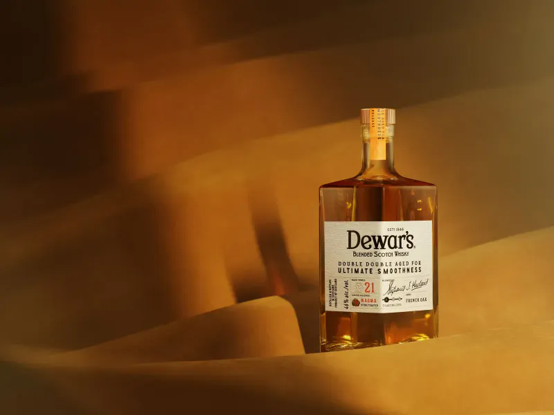 Dewar's Ultimate 21-Year-Old whisky bottle with warm amber glow and label details.