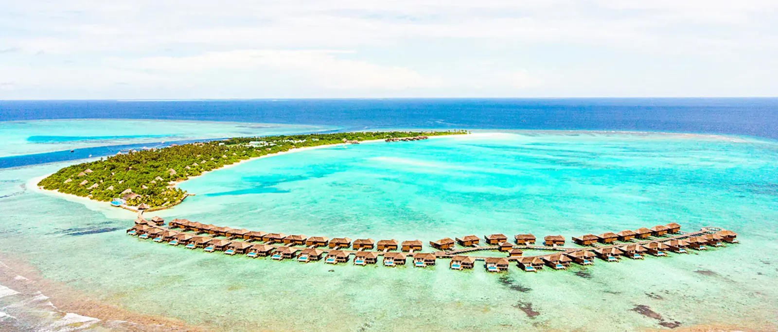 Aerial view of luxury overwater bungalows on a turquoise lagoon surrounding a tropical island