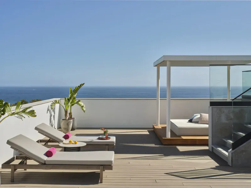 Luxury rooftop terrace at W Algarve Hotel with loungers, plants, fruits, and ocean view.