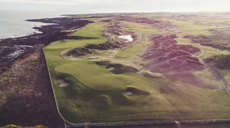 Aerial view of Fairmont St Andrews golf course in Scotland, green fairways and bunkers along rugged coastline.