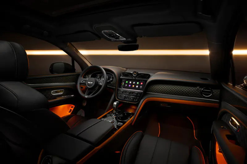 Bentley Black Edition interior with black leather seats, orange ambient lighting, and infotainment display