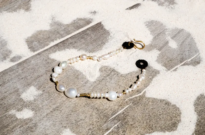 Pebble & Loop pearl bracelet with black loop accents on textured stone surface