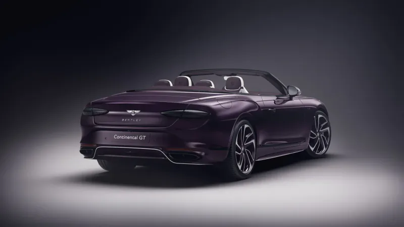Rear view of bespoke purple Bentley Continental GTC Speed convertible with open top on dark studio background