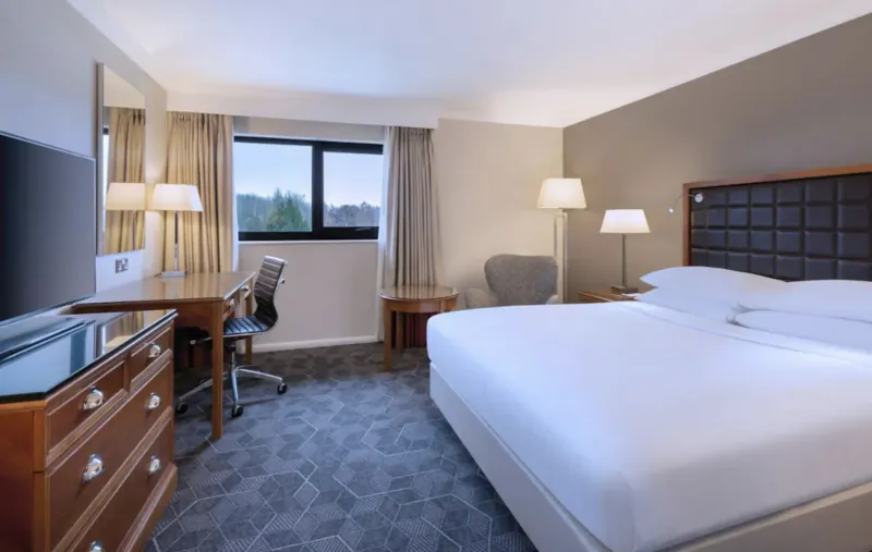 Spacious Delta Hotel by Marriott Swansea room with king bed, desk, TV, lamps, and window view.