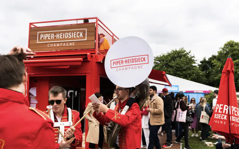 Piper-Heidsieck Champagne Garden at Taste of London: red-uniformed band plays near branded booth and crowd.