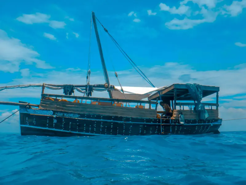 Traditional wooden dhow sailboat with canopy floating on blue ocean in Kisite-Mpunguti Marine Park, Kenya