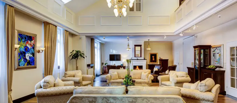 Elegant living room at Grand Hotel Des Bains Kempinski St. Moritz with cream sofas, chandelier, plants, and art.