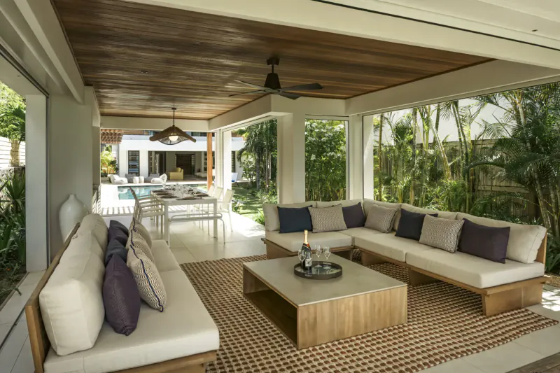 Spacious outdoor lounge at Villa Diamond, Mauritius: white L-shaped sofa with cushions, wooden coffee table, poolside garden view.