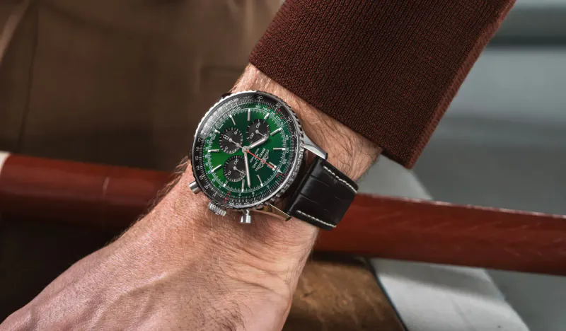 Close-up of green-dial Breitling Navitimer chronograph watch on man's wrist with brown leather strap