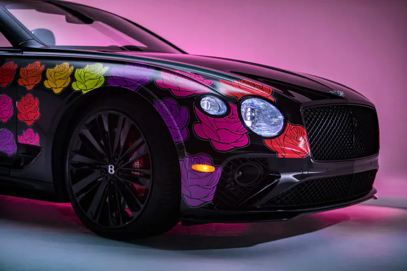 Bentley car with vibrant multicolored rose graphics on magenta background, front view