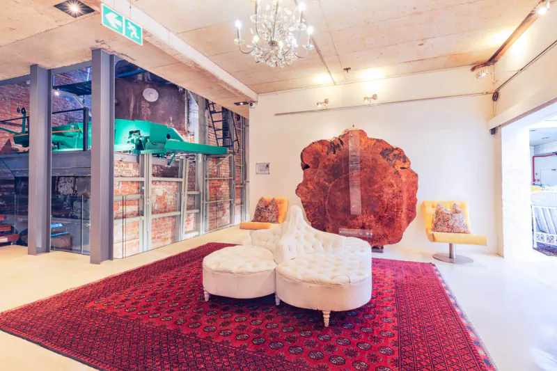 Modern Turbine Boutique Hotel lobby with large wood sculpture, white lounge chairs on red rug, green car mezzanine, exit sign.