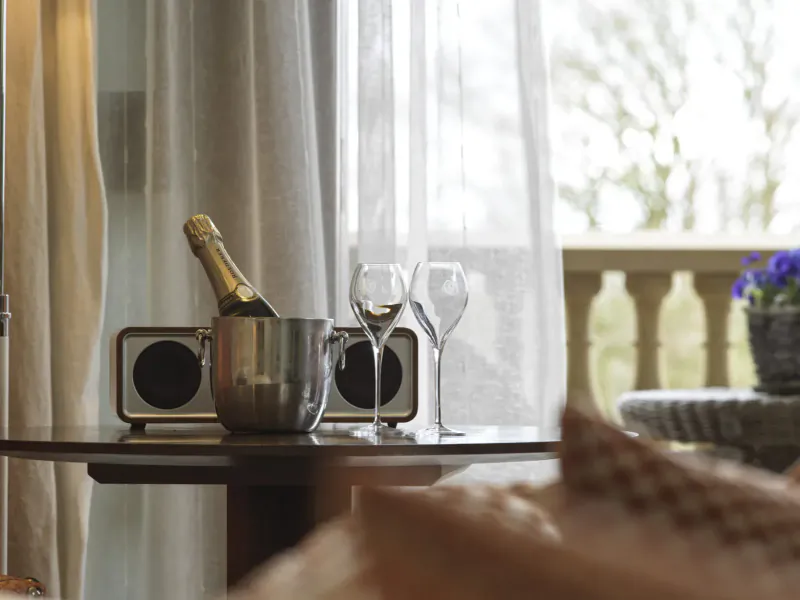 Champagne bottle in ice bucket, two wine glasses, retro speaker on table by sheer curtains and balcony at Northcote Hotel