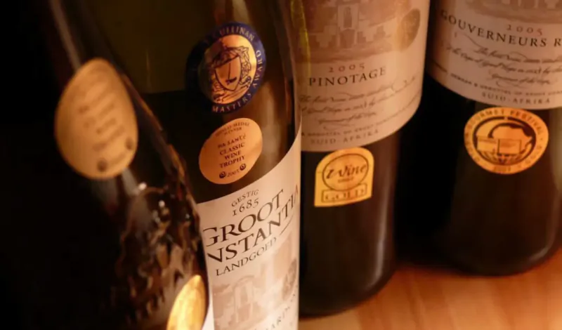Three Groot Constantia wine bottles: Pinotage, Gouverneurs and Groot Constantia, on wooden surface