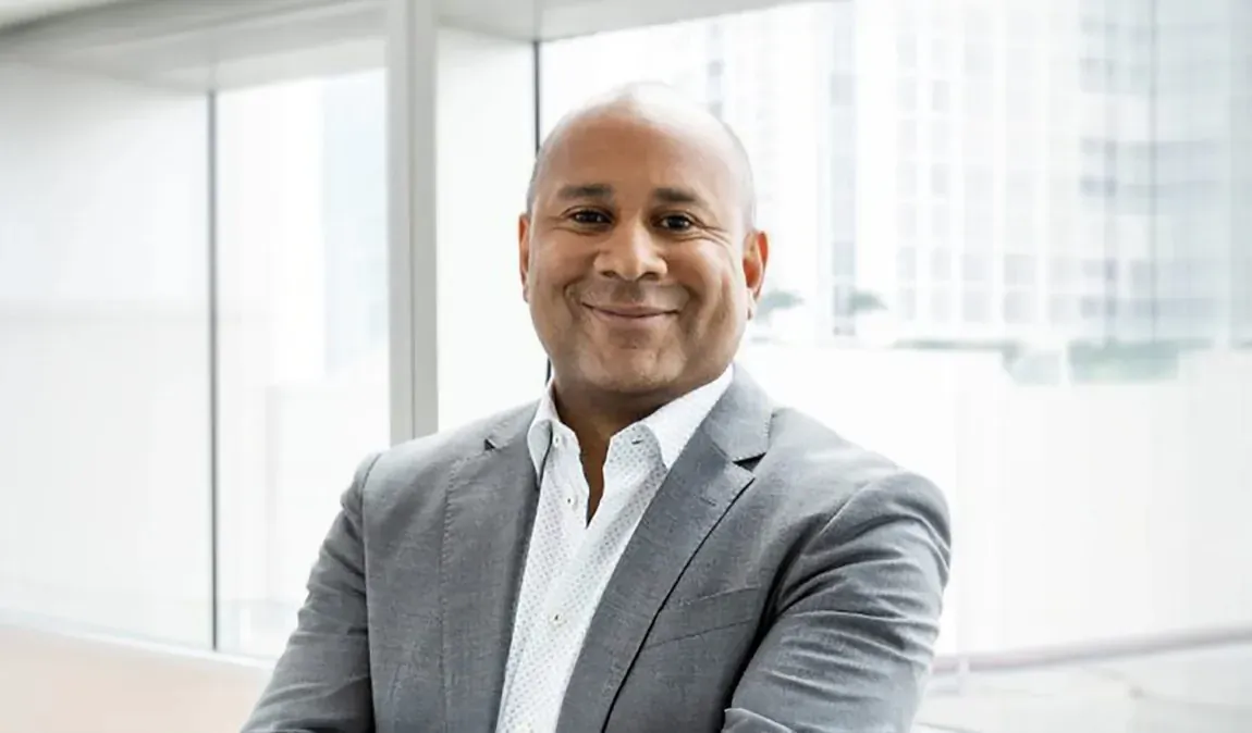 Walter Littlejohn, new Chief Sales Officer of SeaDream Yacht Club, smiling in gray suit in modern office.