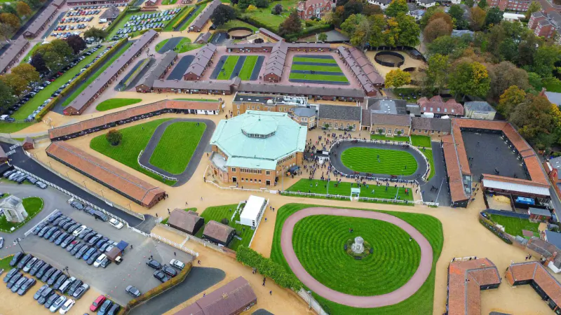 Aerial view of Tattersalls horse auction complex with central green-domed ring, training tracks, stables, and autumn trees.