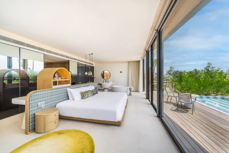 Modern bedroom in SO/ Maldives villa with king bed, ensuite bathroom, and infinity pool view.