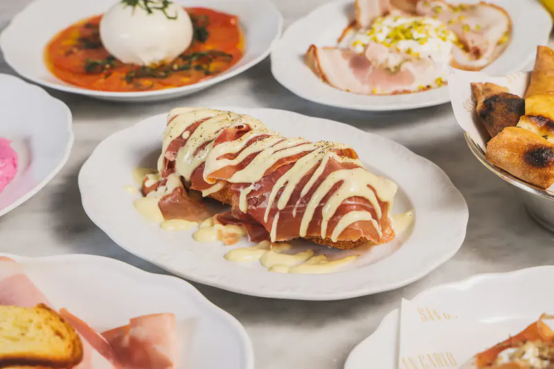 Assortment of Italian dishes on plates: burrata, prosciutto, stuffed pastry with sauce, and fried bites