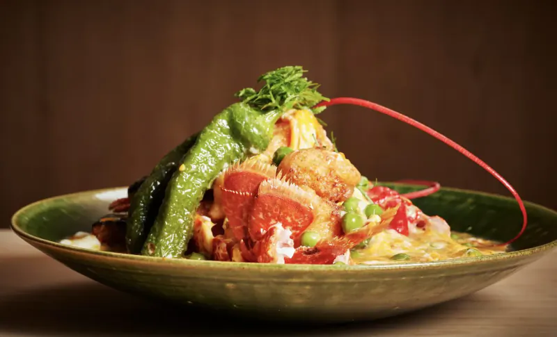 Kaiseki dish of lobster, green peppers, yellow veggies, and garnishes on green plate