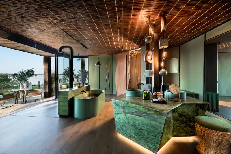 Lavish Lolebezi luxury safari lounge in Zambia with green marble counter, curved seating, pendant lights, and lake view.