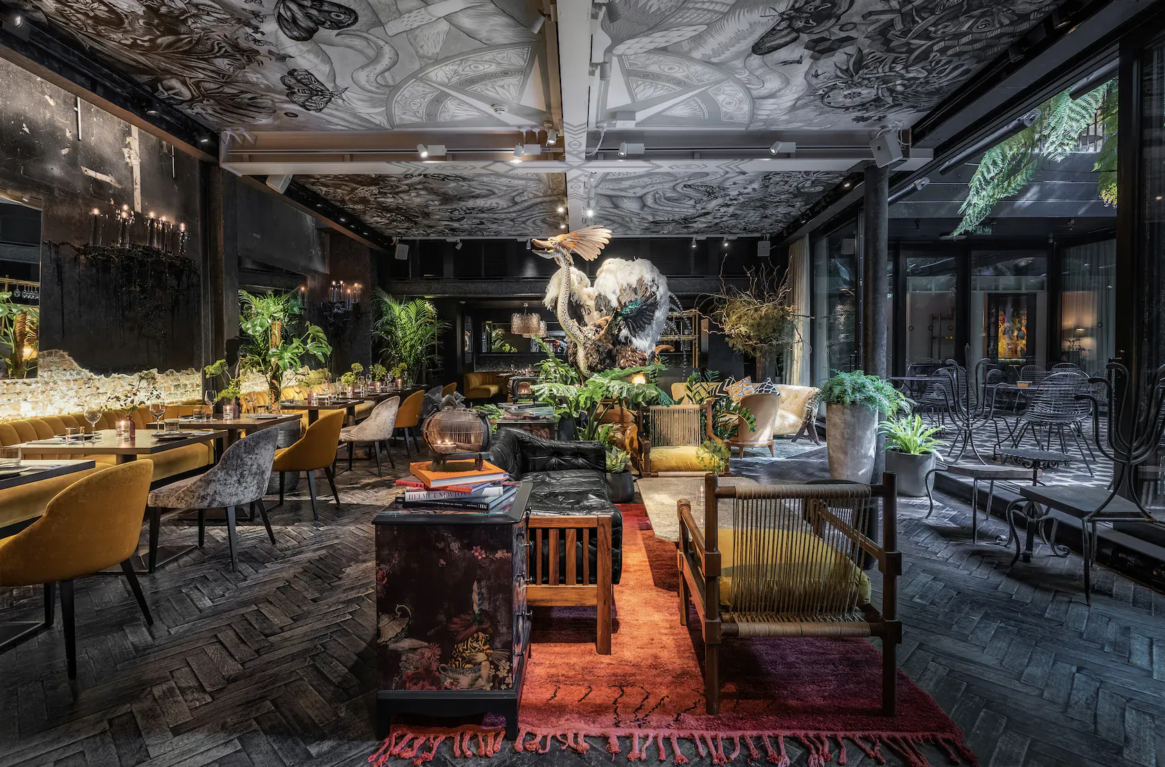 Stylish YOPO jungle-themed interior in Fitzrovia with ornate ceiling, large floral sculpture, plants, eclectic seating, and bar.