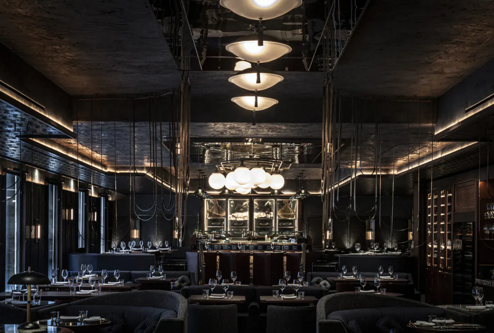 Elegant Lucky Cat Mayfair restaurant interior with mirrored walls, glowing pendant lights, sleek bar, and empty tables.