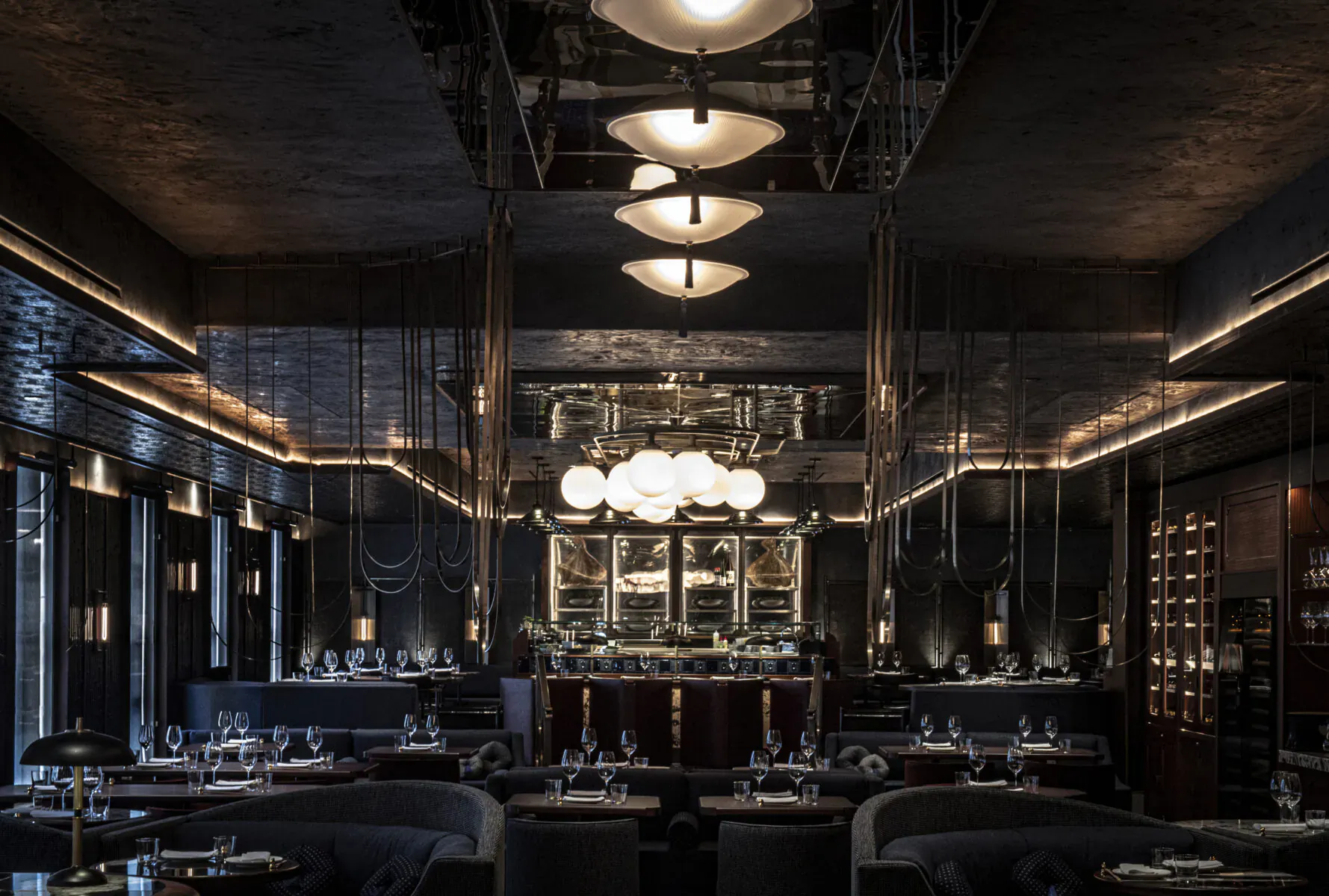 Elegant Lucky Cat Mayfair restaurant interior with mirrored walls, glowing pendant lights, sleek bar, and empty tables.