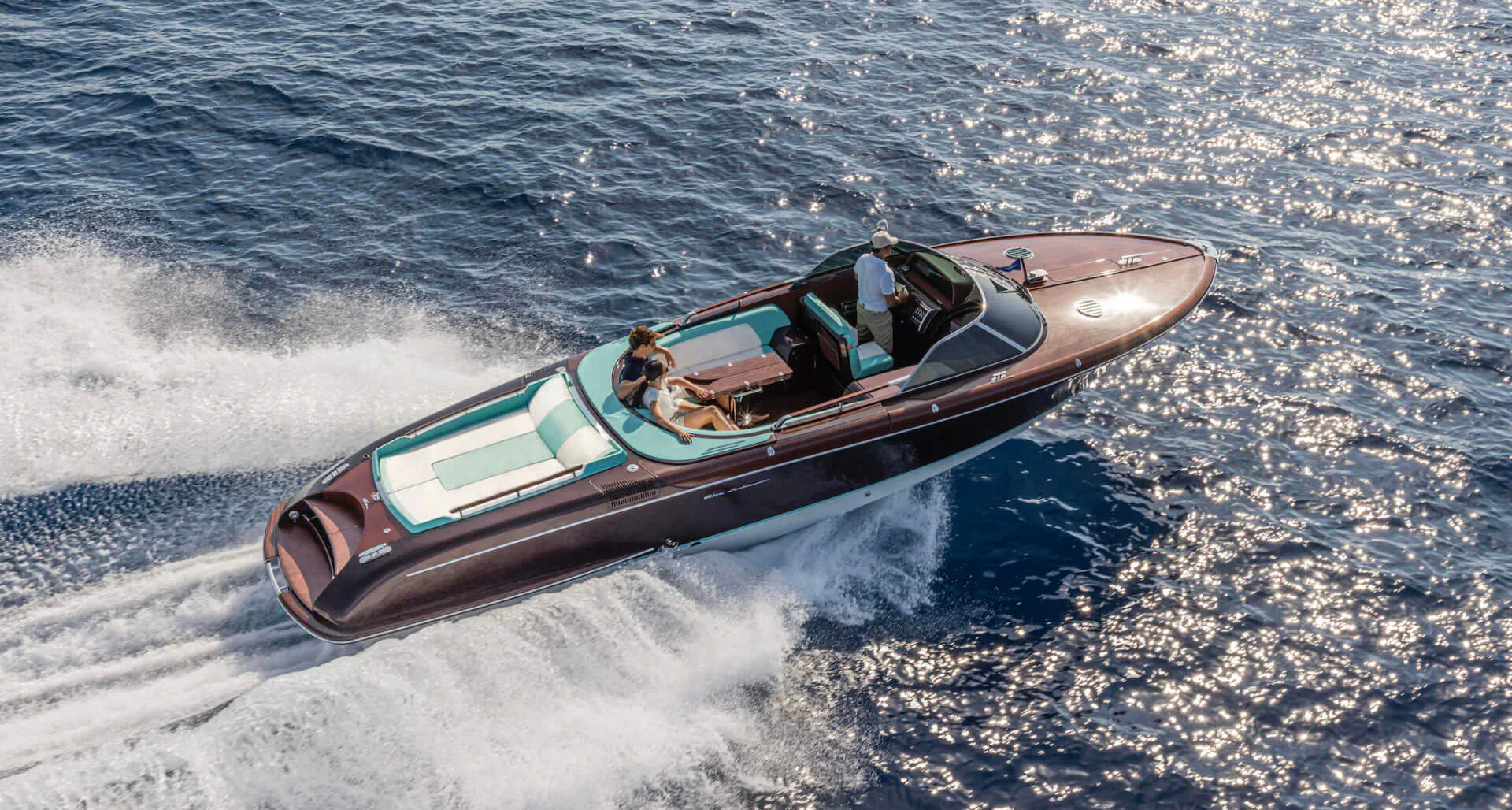 Riva Anniversary open powerboat speeding across the sea with two people aboard, aerial view