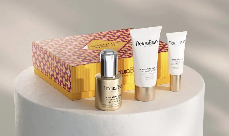 Naos skincare gift set in pink patterned box with gold serum, white tubes on white surface