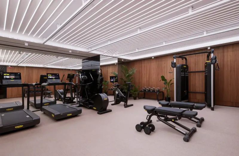 Modern gym at art'otel Rome with treadmills, exercise bikes, weights bench, wood panels, and mirrors.